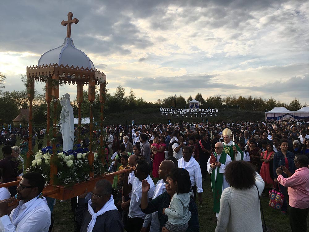 La statue de la Vierge portée en procession sous un dais au milieu de la foule des pèlerins