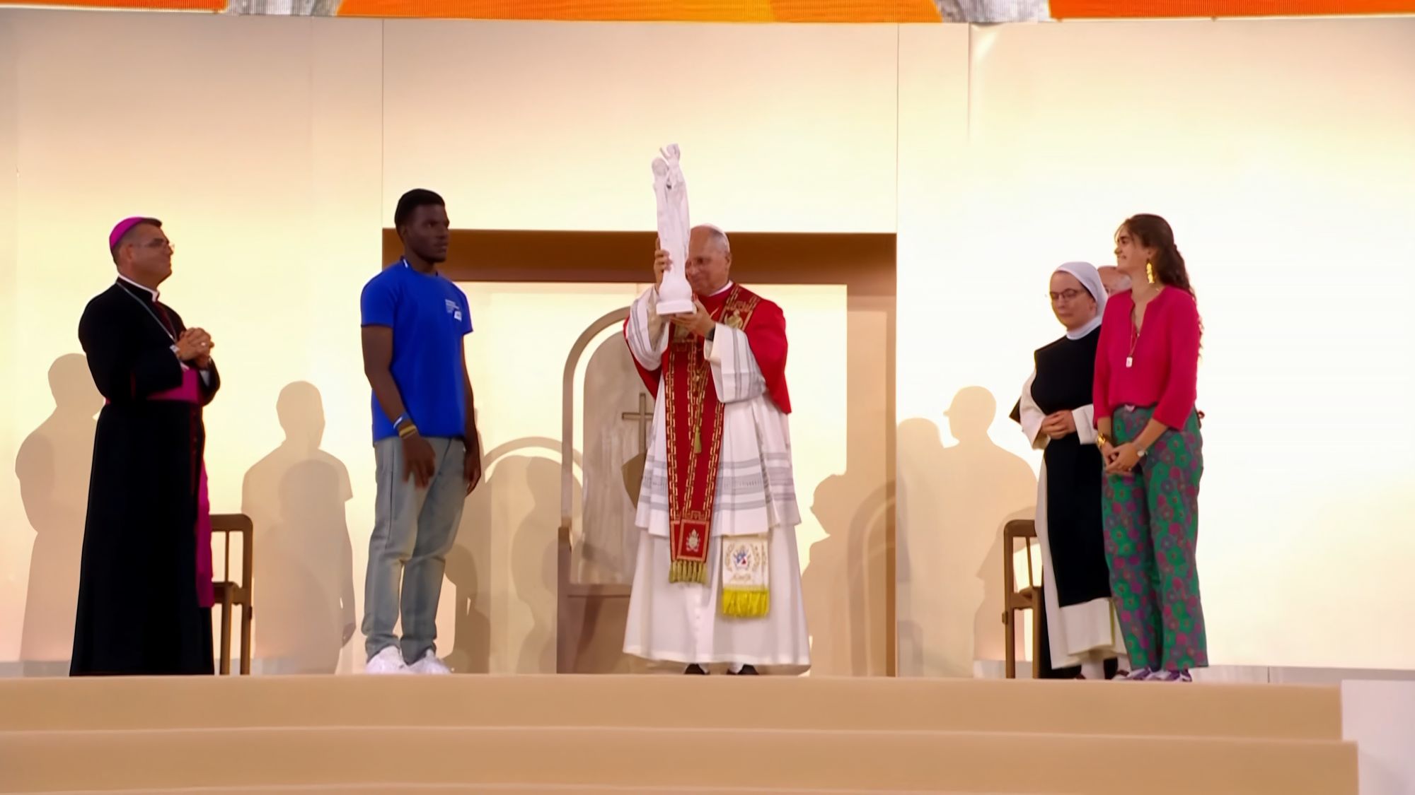Le pape Léon XIV élève la statue de Notre-Dame de France sur l'estrade du Stade de France, entouré de jeunes, d'une religieuse et d'un évêque