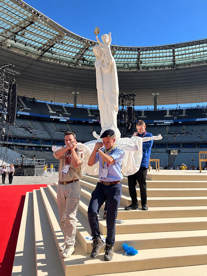 Des scouts s'entraînent à porter la statue de 2 mètres de Notre-Dame de France sur les marches de l'estrade du Stade de France