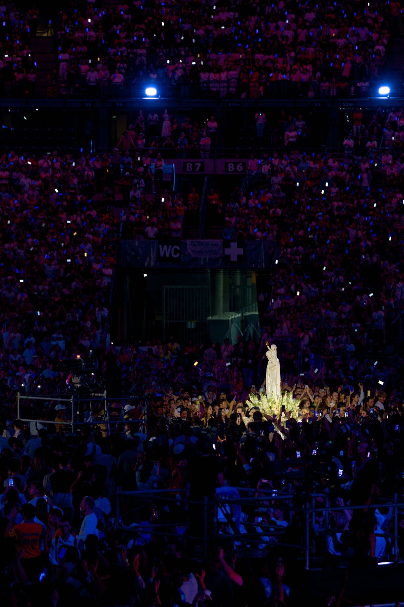 La statue de Notre-Dame de France portée dans la foule, devant les tribunes éclairées par les téléphones