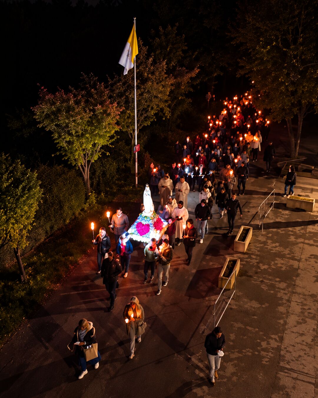 La procession passe devant le drapeau du Vatican.
