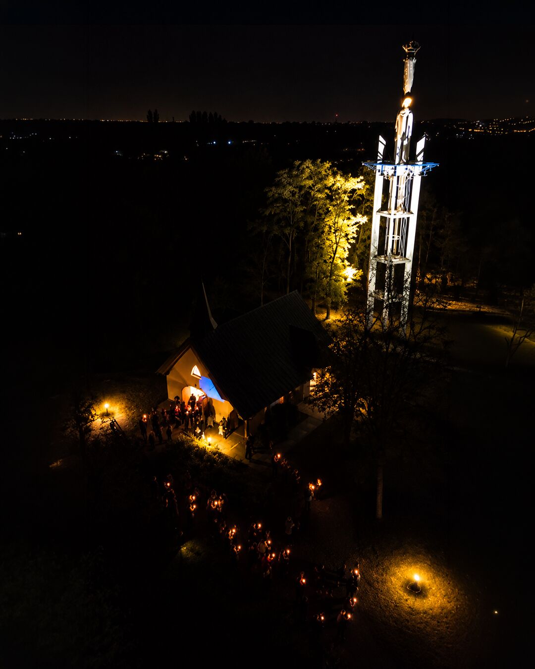 Le sanctuaire vu du ciel : la chapelle, la statue monumentale et le cortège de lumières.